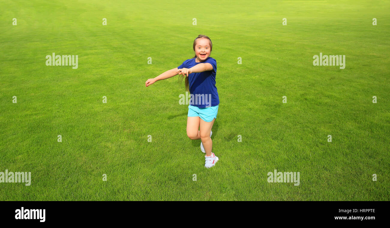 Bambina in esecuzione su erba verde sullo sfondo Foto Stock