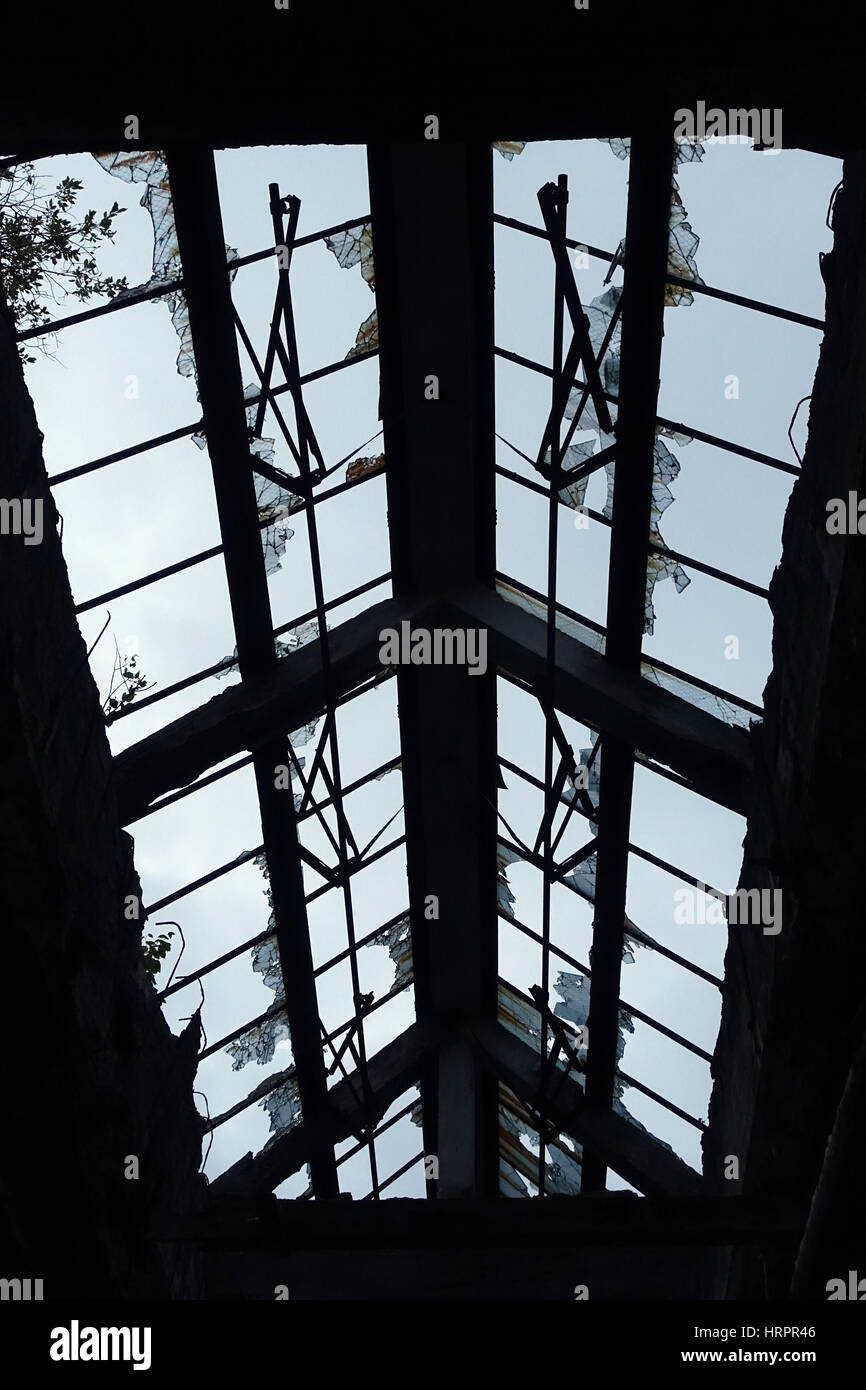 Guardando il cielo attraverso le finestre rotte in un edificio abbandonato. Foto Stock