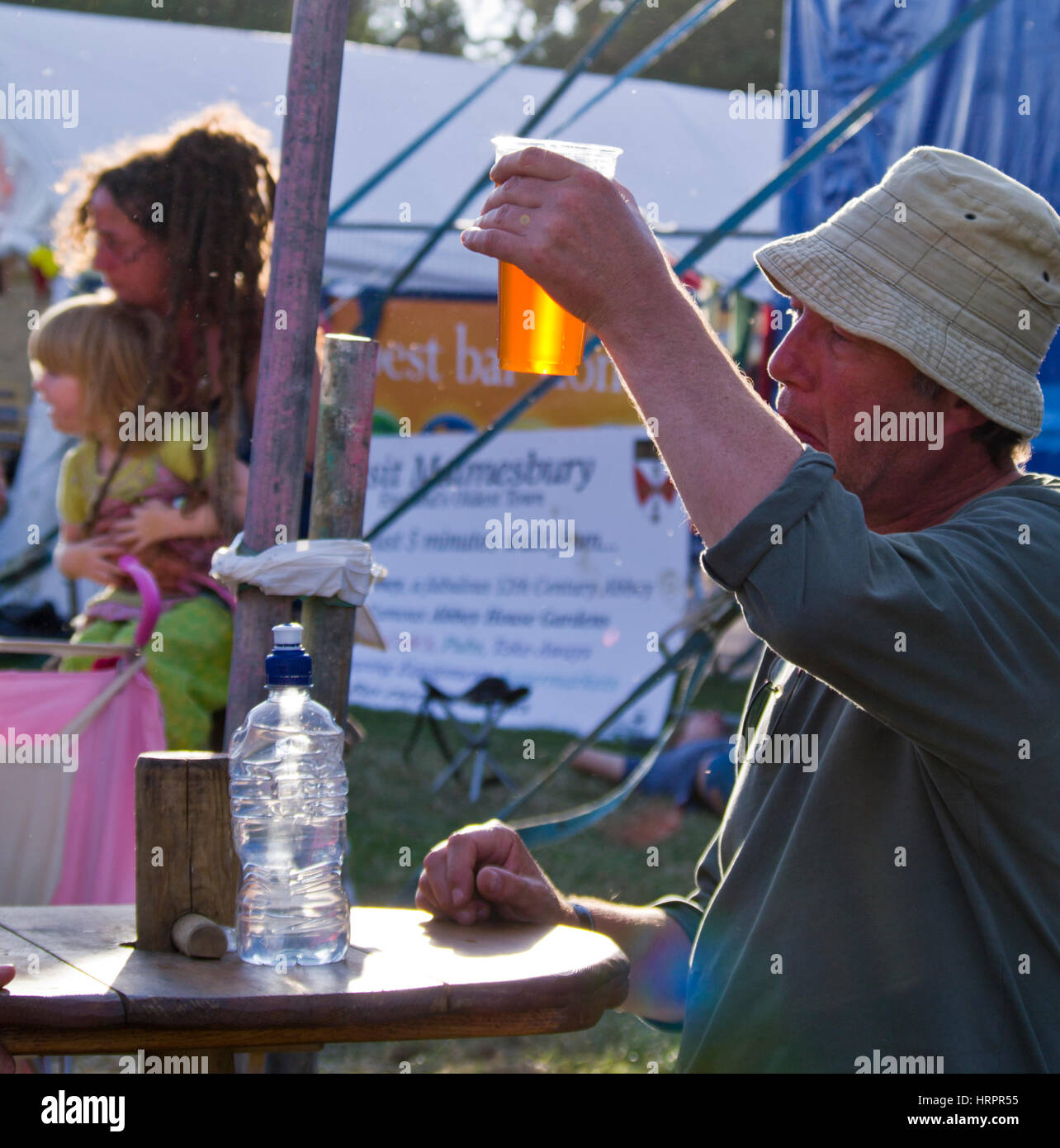 Al 2010 Womad Festival un uomo solleva un bicchiere per esaminare il colore della birra. Foto Stock