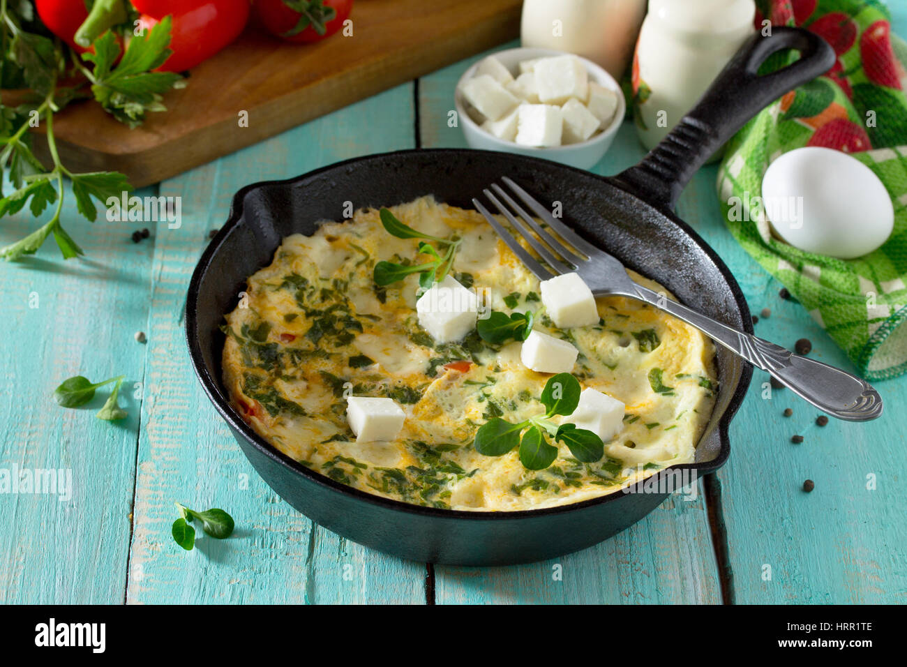 Frittata con peperoni, pomodori e formaggio feta in una ghisa padella su di un tavolo di legno. Il concetto di una sana nutrizione e dietetica. Il bulgaro cuis Foto Stock