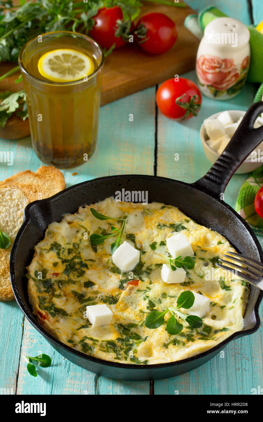 Frittata con peperoni, pomodori e formaggio feta in una ghisa padella su di un tavolo di legno. Il concetto di una sana nutrizione e dietetica. Il bulgaro cuis Foto Stock