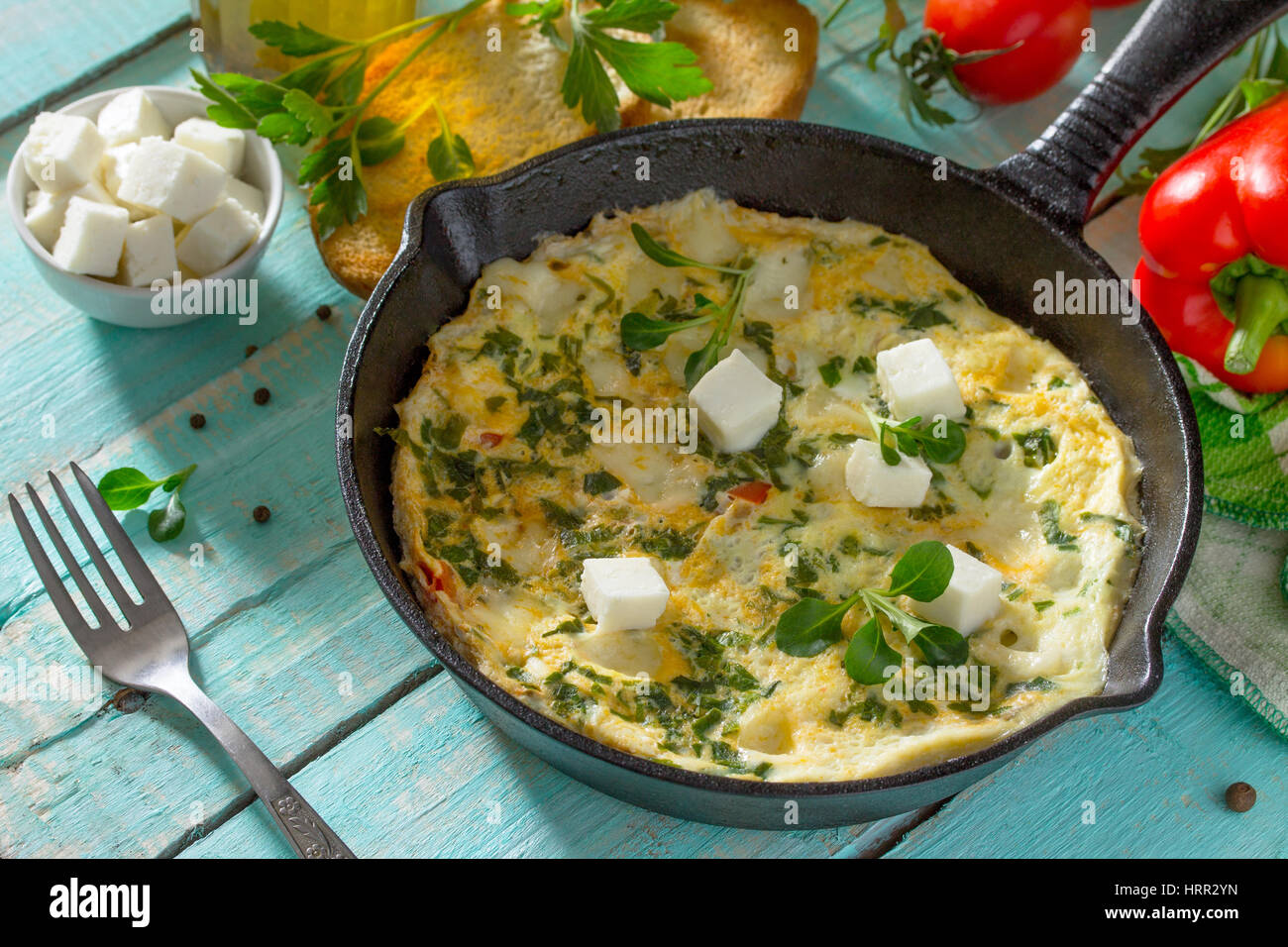 Frittata con peperoni, pomodori e formaggio feta in una ghisa padella su di un tavolo di legno. Il concetto di una sana nutrizione e dietetica. Il bulgaro cuis Foto Stock