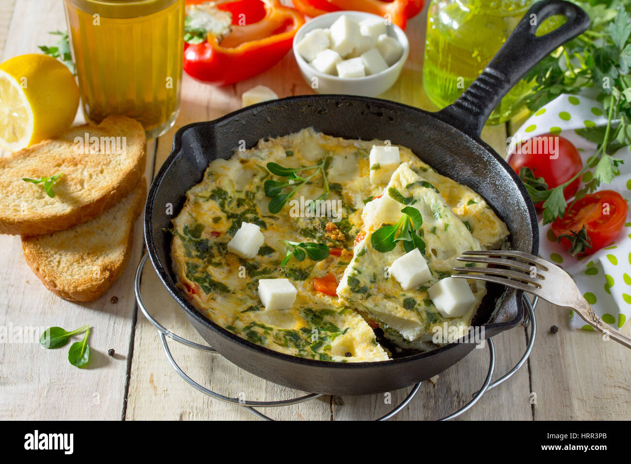 Frittata con peperoni, pomodori e formaggio feta in una ghisa padella su di un tavolo di legno. Il concetto di una sana nutrizione e dietetica. Il bulgaro cuis Foto Stock