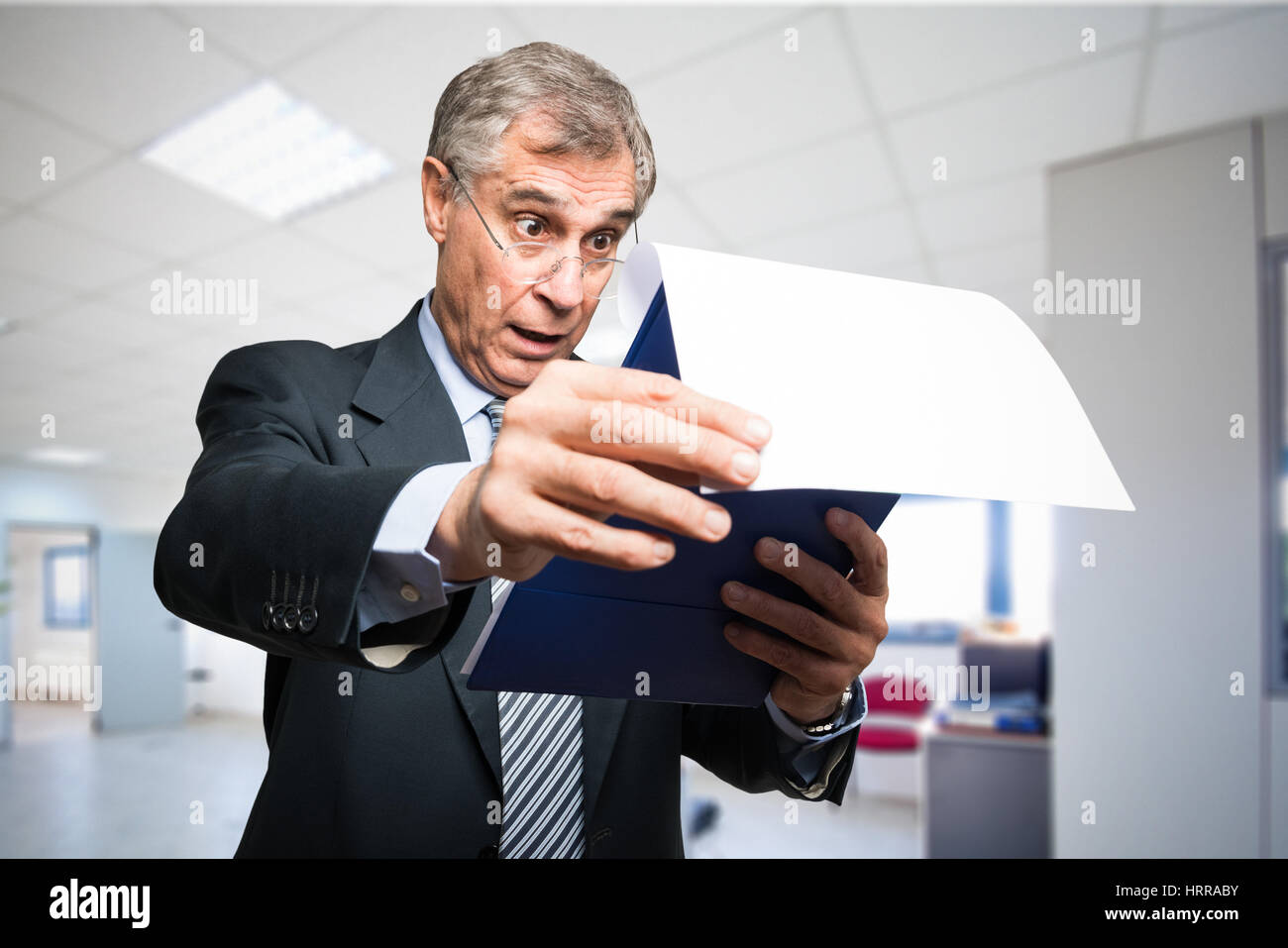 Imprenditore sorpreso la lettura di un documento nel suo ufficio Foto Stock
