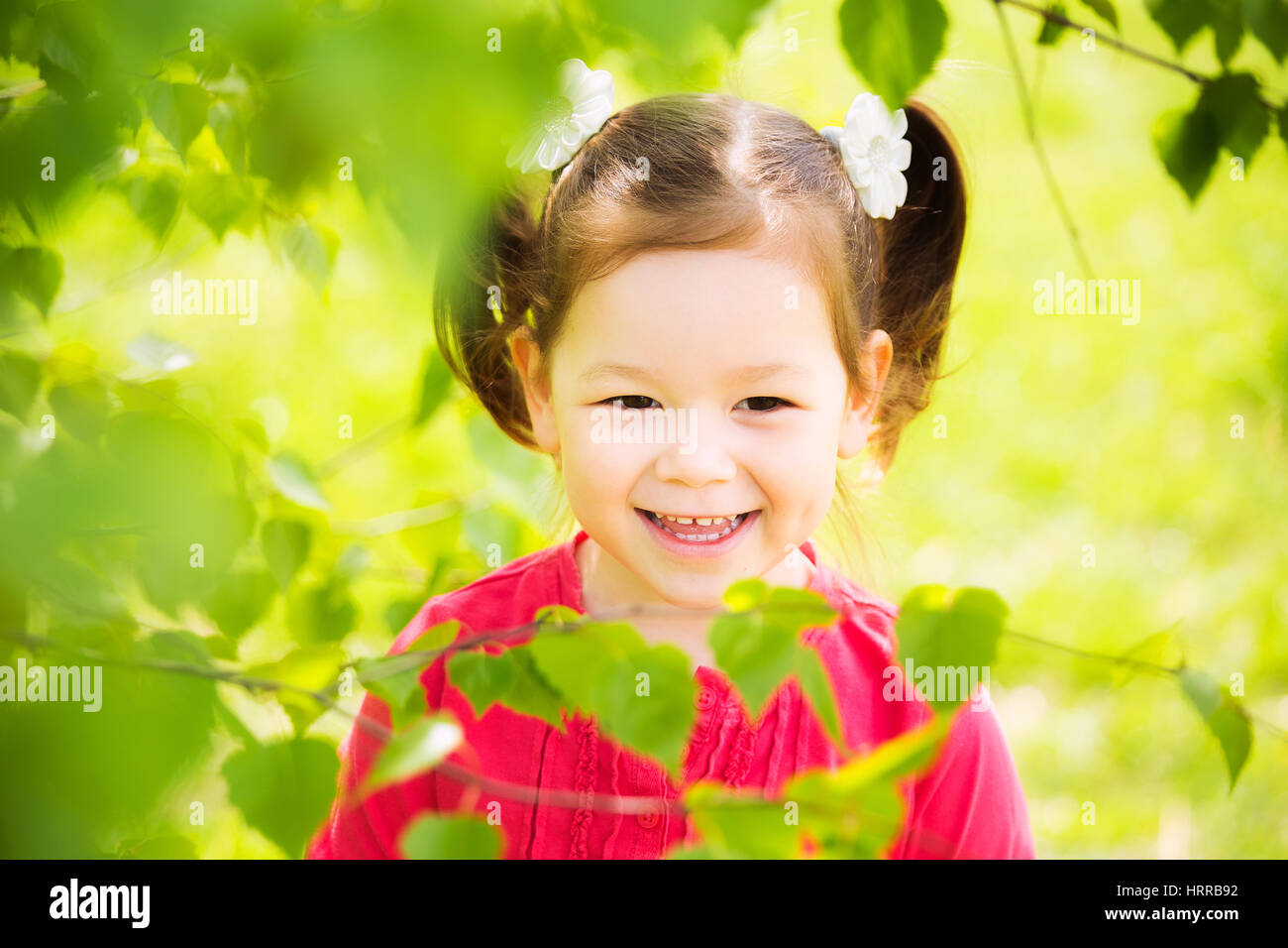 Closeup ritratto di carino divertente ragazza ridere di quattro anni a giocare allegramente fuori in primavera soleggiata città park. Orizzontale della fotografia a colori Foto Stock
