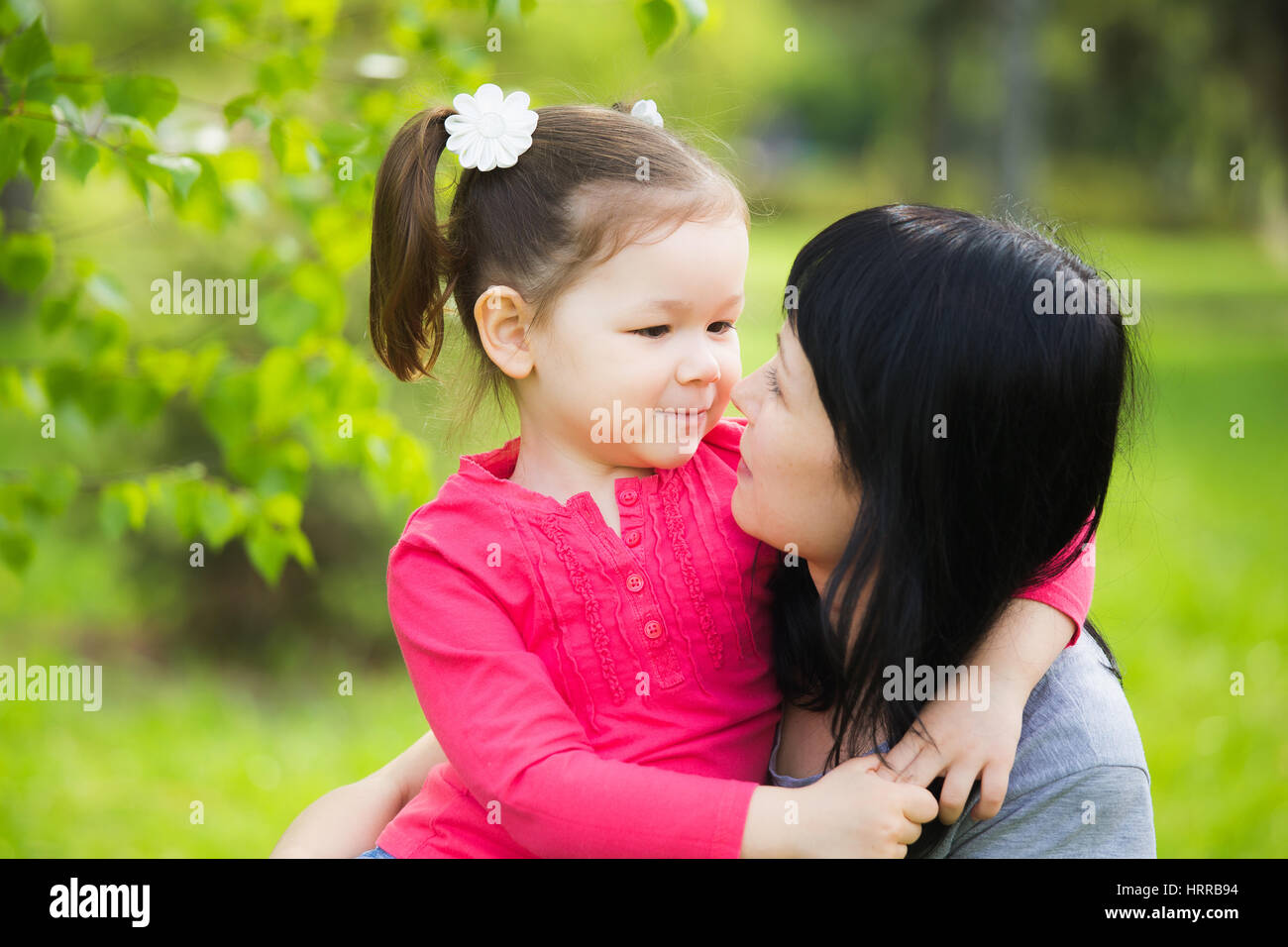 Vista dettagliata dei profili di felice madre e figlia nella primavera del parco. Poco funny girl di 4 anni di età al di fuori a giocare con i suoi genitori in primavera il parco della città Foto Stock