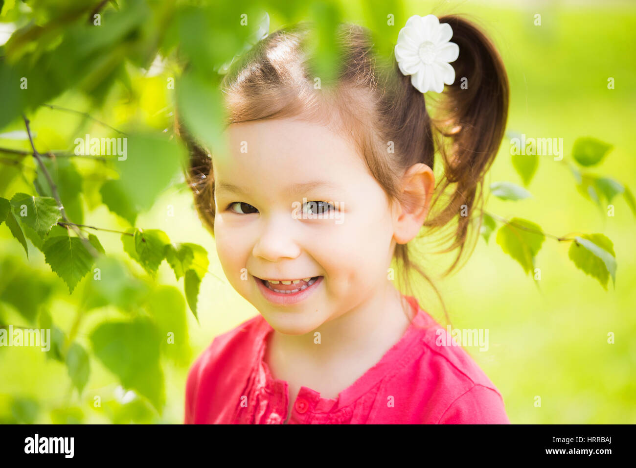 Closeup ritratto di carino divertente ragazza ridere di quattro anni a giocare allegramente fuori in primavera soleggiata città park. Orizzontale fotografia a colori. Foto Stock