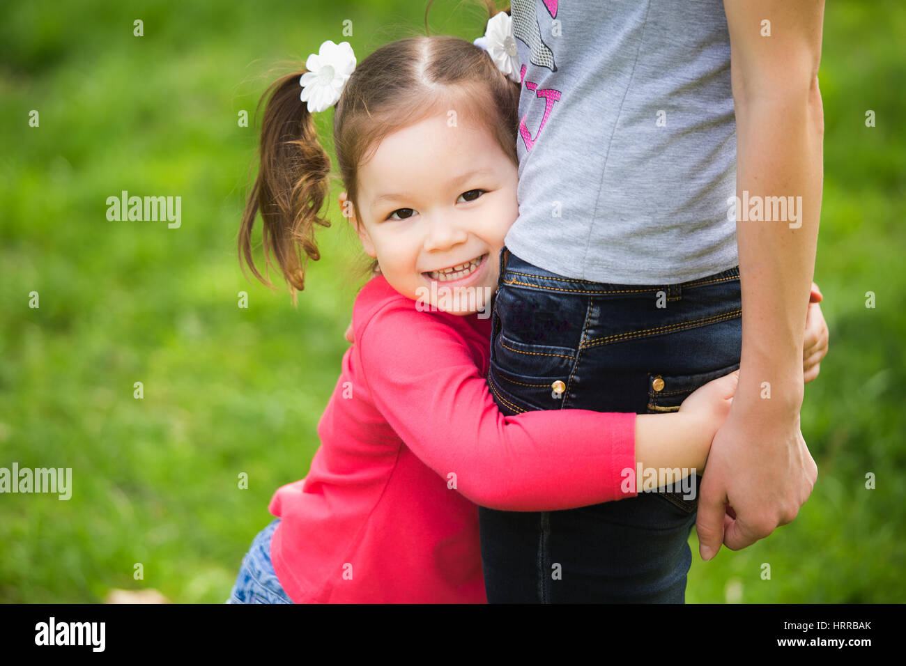 Closeup ritratto di famiglia felice. Poco funny girl di 4 anni di età al di fuori a giocare con la sua mamma nella primavera del parco della città. Orizzontale della fotografia a colori Foto Stock