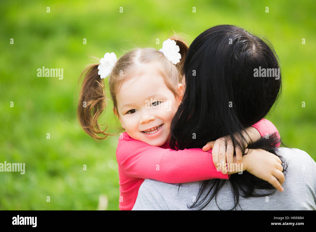 Closeup ritratto di famiglia felice. Poco funny girl di 4 anni di età al di fuori a giocare con la sua mamma nella primavera del parco della città. In prossimità della faccia sorridente di bellezza Foto Stock