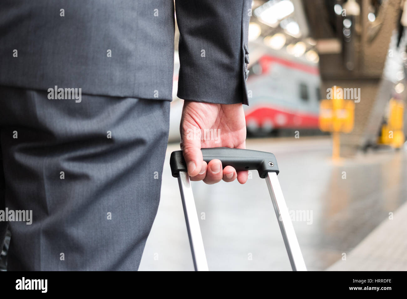 Dettaglio di un imprenditore tira un carrello in una stazione ferroviaria Foto Stock