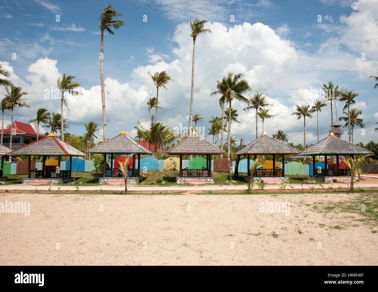 Numerosi rifugi sulla spiaggia utilizzato per il rilassamento e il riparo dal sole con palme in background e nessuno attorno, Singkawang Borneo. Foto Stock