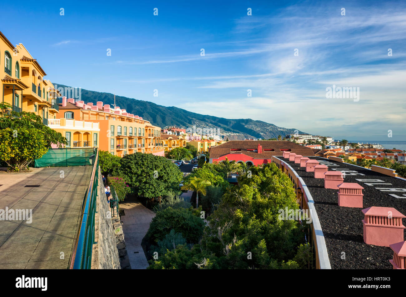 Los Cancajos, La Palma. Una vista dall'Hotel Las Olas appartamenti vacanze cercando lungo la costa verso Santa Cruz a pochi chilometri lungo la costa. Il giallo hotel fronti conducono verso il litorale distante mentre i tetti di edifici inferiore nella curva dalla parte inferiore destra della fotografia. Si tratta di una chiara mattina di sole con solo qualche luce nuvole nebuloso linger sopra l'oceano. Fotografato con una Ricoh GRII fotocamera. Foto Stock