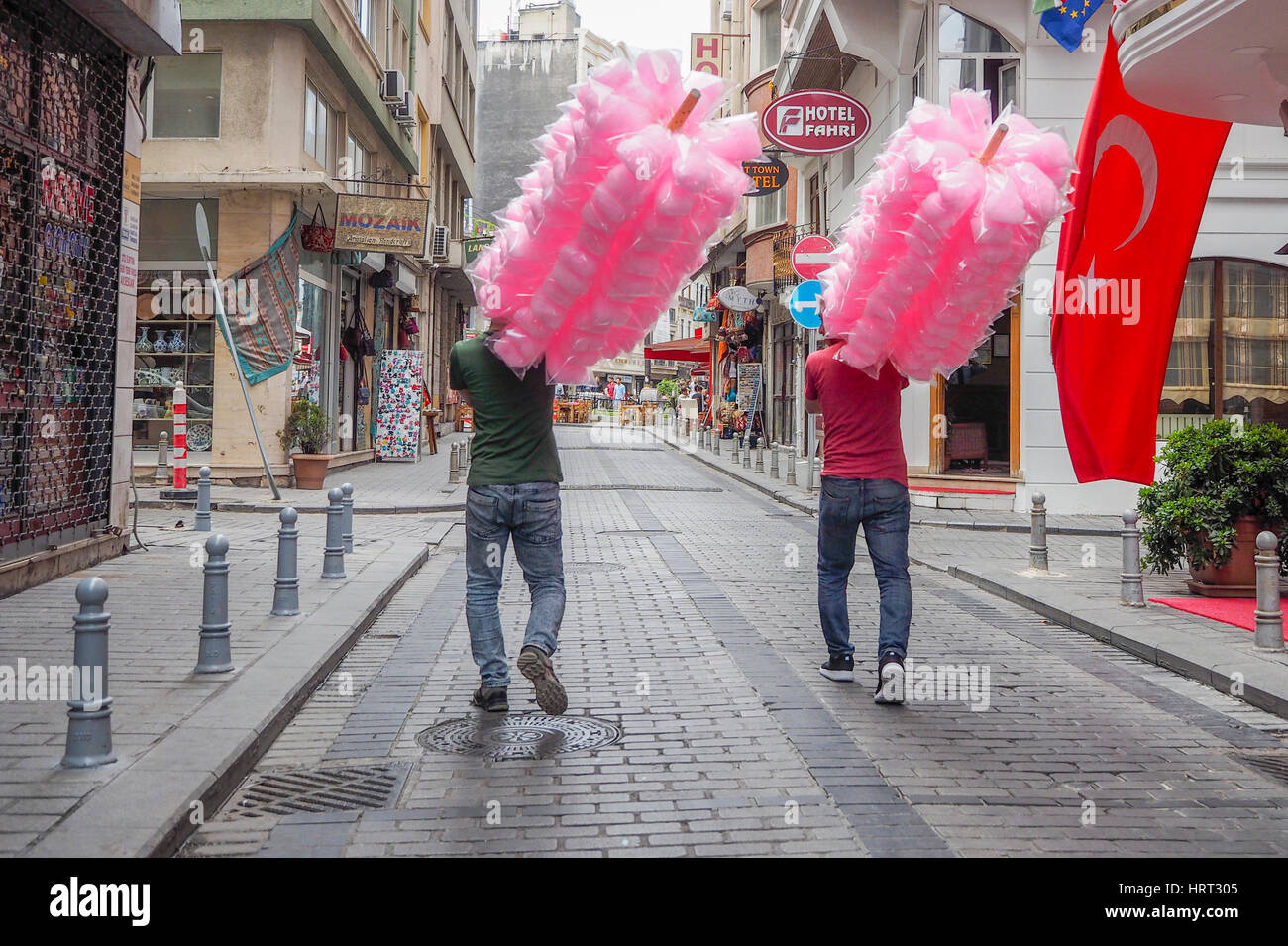Rosa Candy Floss insaccato e trattenuto sul polo viene fornito da due uomini turco Istanbul TURCHIA Foto Stock