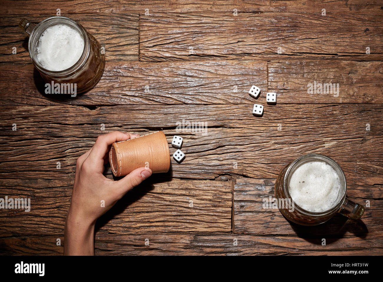 Dado da gioco gioco su un vecchio tavolo di legno con boccale di birra Foto Stock