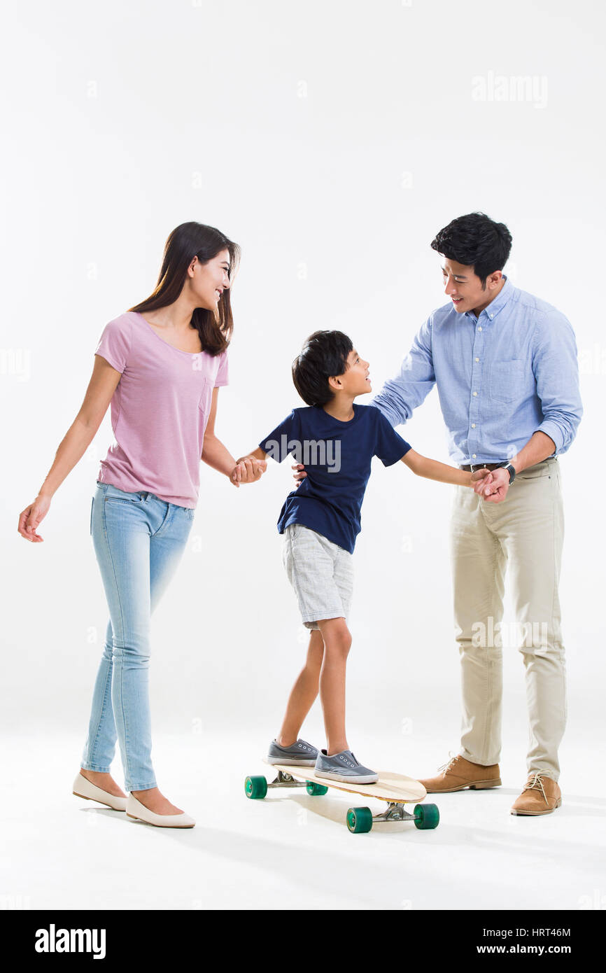 Due genitori insegnare figlio lo skateboard Foto Stock
