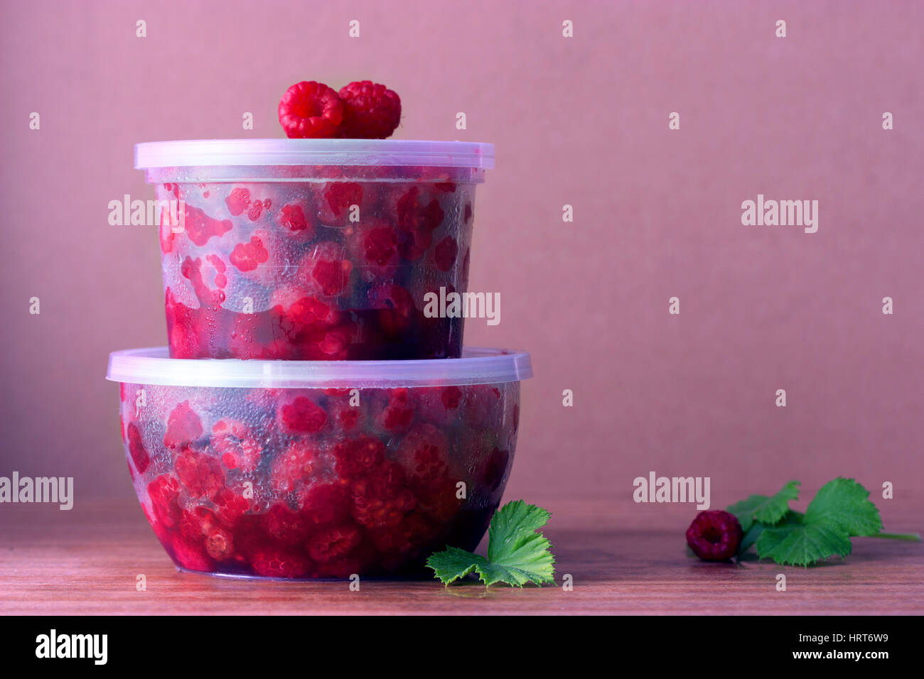 Lampone nella scatola rotonda con foglie di menta sullo sfondo di legno vecchio Foto Stock