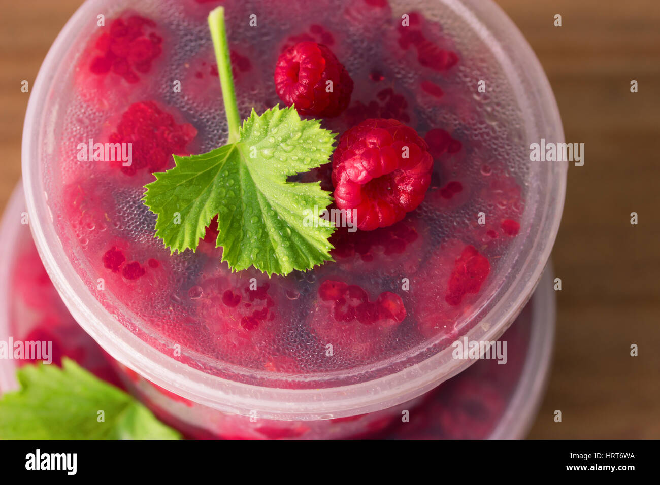 Lampone nella scatola rotonda con foglie di menta sullo sfondo di legno vecchio Foto Stock