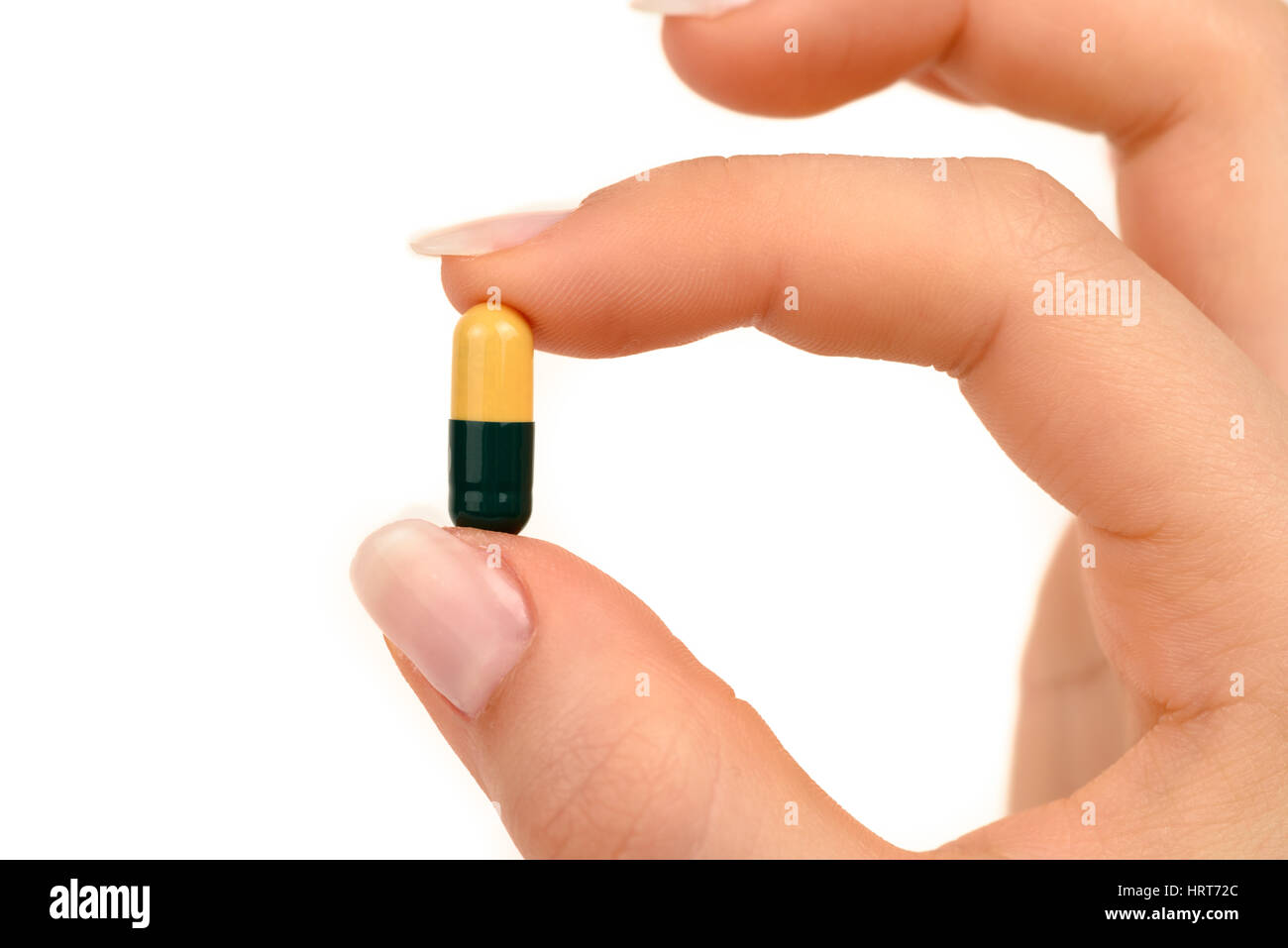 La mano di una donna che mantiene una pillola su sfondo bianco Foto Stock