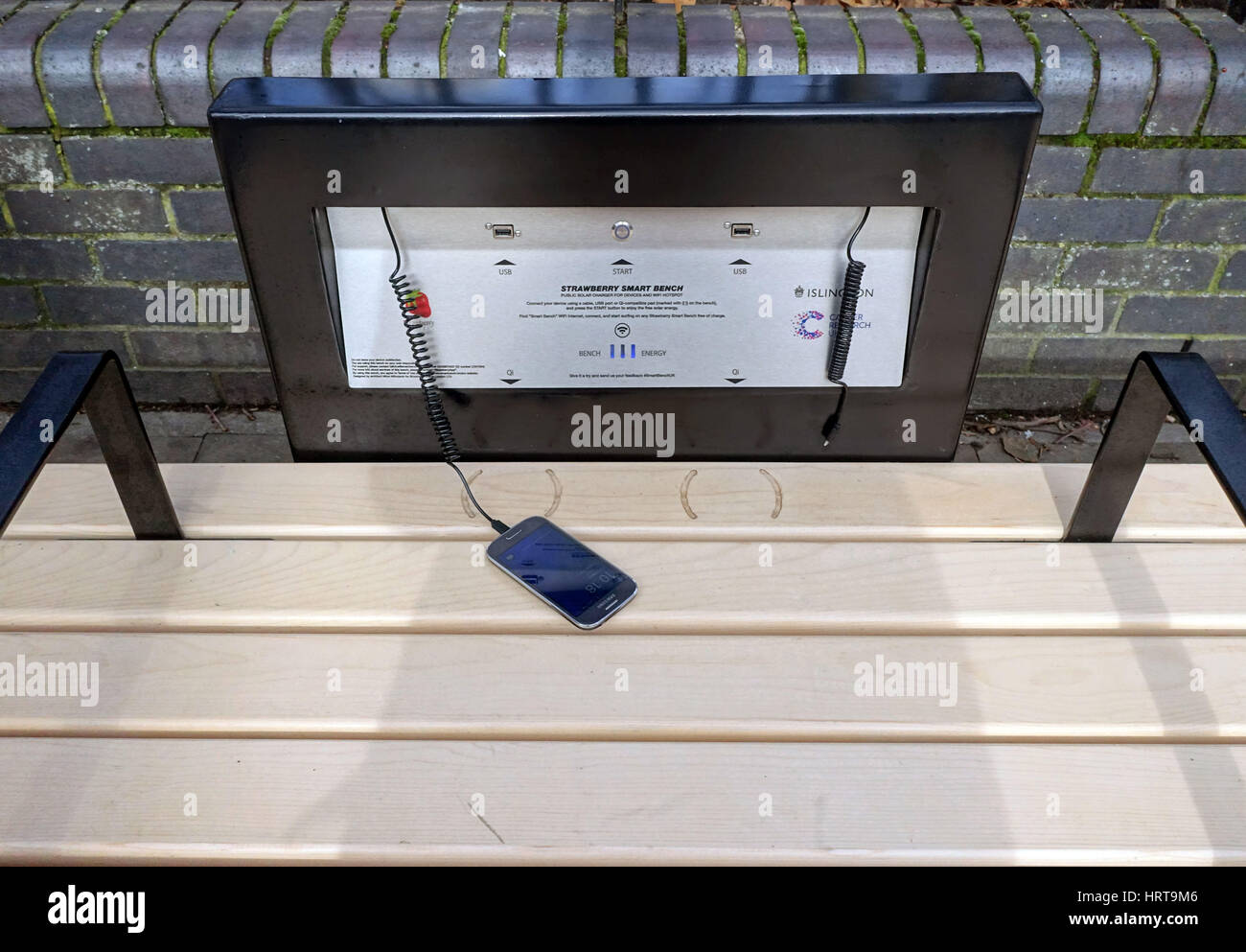 Pubblico di energia solare di 'smart panchina' per la ricarica di dispositivi mobili, Islington, Londra Foto Stock