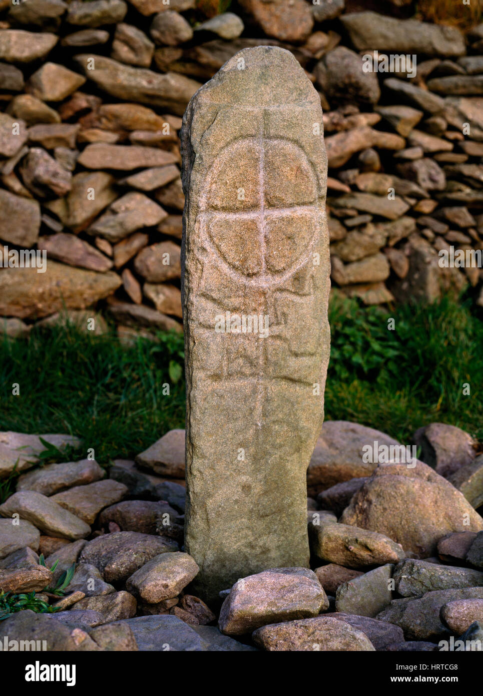 Uno dei primi cristiani pietra inscritto in piedi in un letto di forma rettangolare di pietre (leacht) a fianco di Gallarus a barchetta oratorio, Dingle, Co. Kerry, Irlanda. Foto Stock