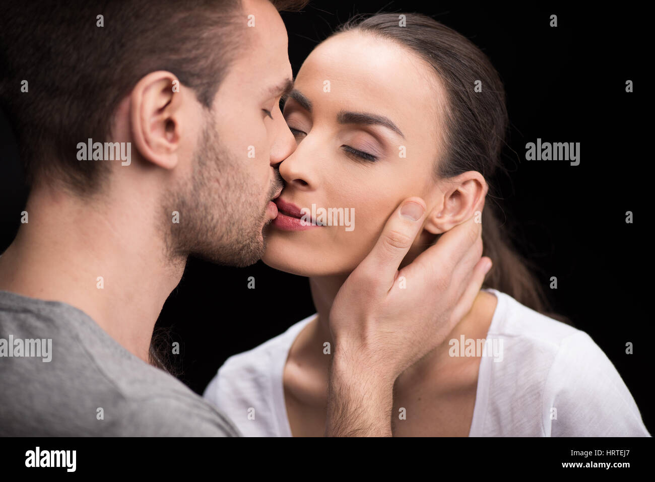Ritratto di uomo sensualmente kissing donna su nero Foto Stock