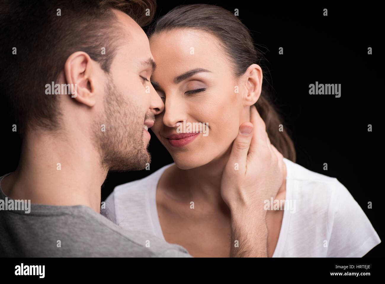 Ritratto di coppia felice in amore con gli occhi chiusi su nero Foto Stock