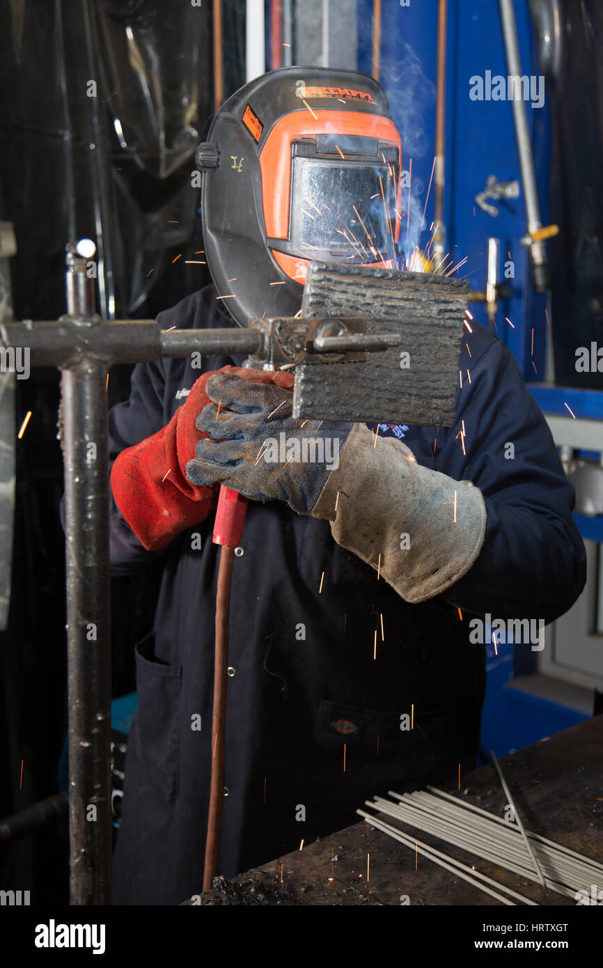 Un saldatore a lavorare utilizzando una maschera protettiva Foto Stock