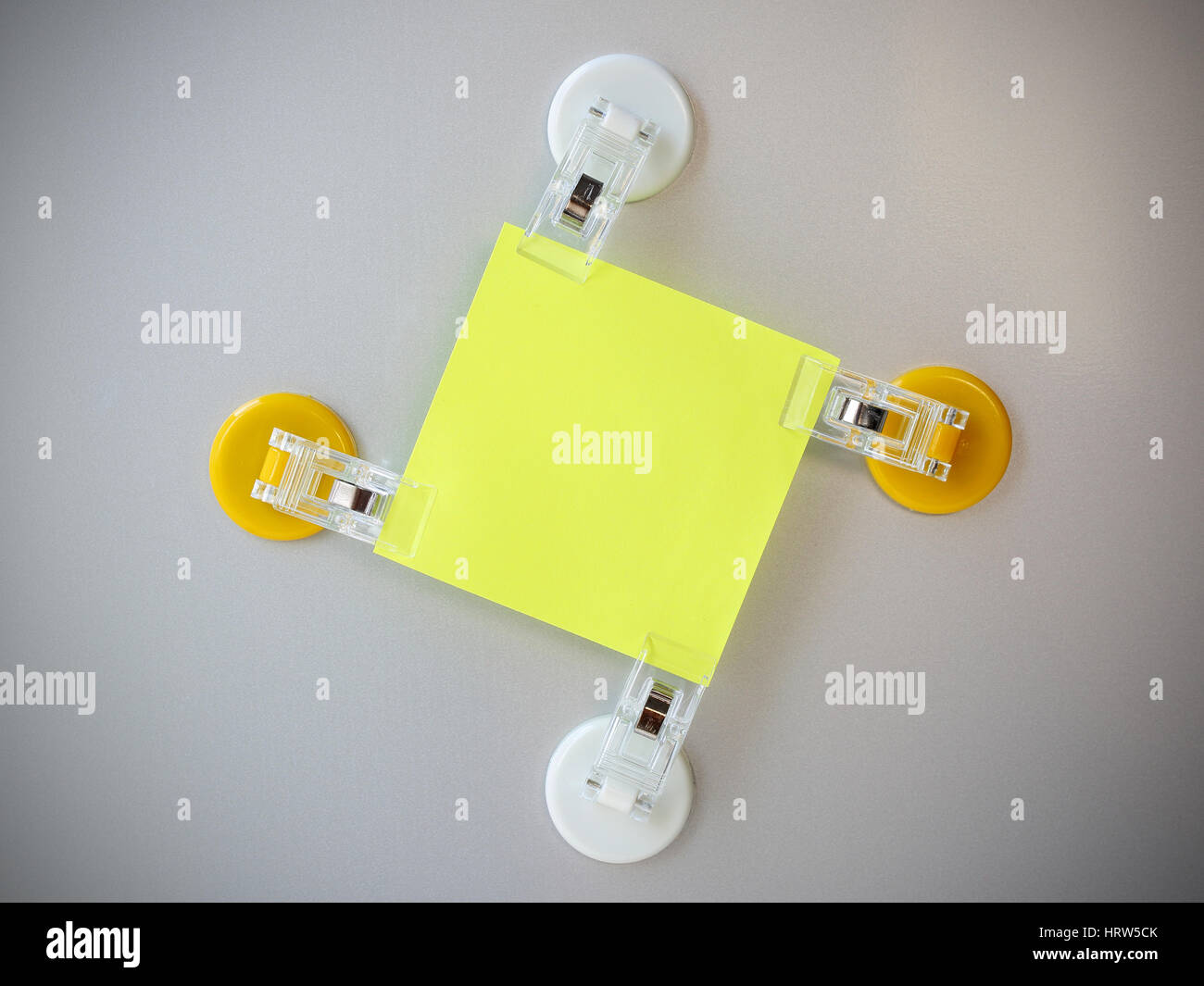 Giallo post it clip di bianco e il fermaglio giallo magnete sul frigorifero grigio Sfondo. Foto Stock
