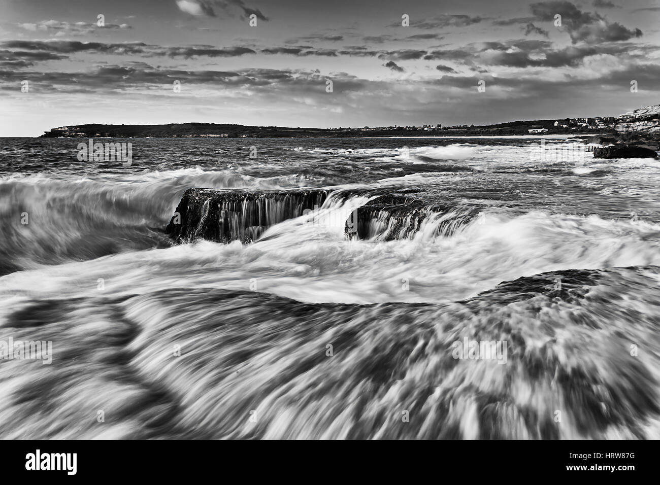 Forte di surf e splash wave rotto sulla riva vicino a Maroubra Beach a Sydney, Australia Pacific Coast. Mattina calda luce sul bianco blu oceano e acqua Foto Stock