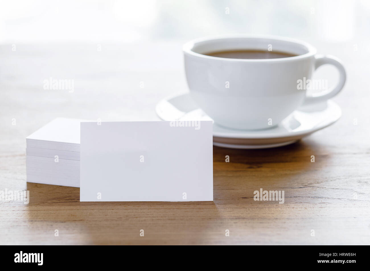 Blank business cards e la tazza di caffè sul tavolo di legno. Corporate branding stazionaria mock up. Foto Stock