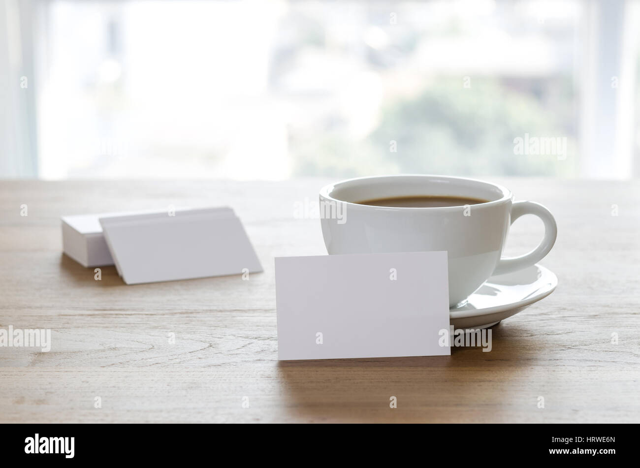 Blank business cards e la tazza di caffè sul tavolo di legno. Corporate branding stazionaria mock up. Foto Stock