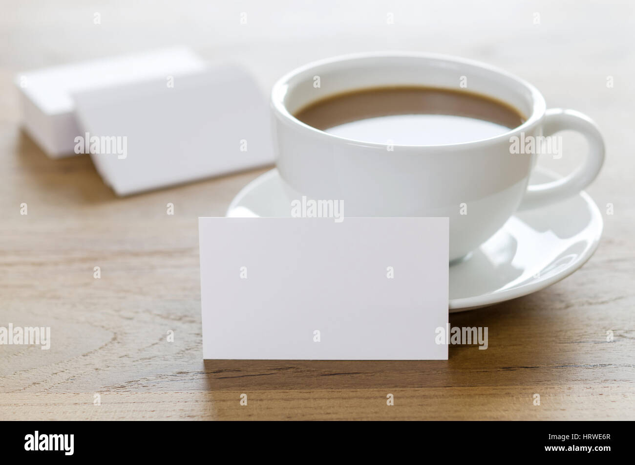 Blank business cards e la tazza di caffè sul tavolo di legno. Corporate branding stazionaria mock up. Foto Stock