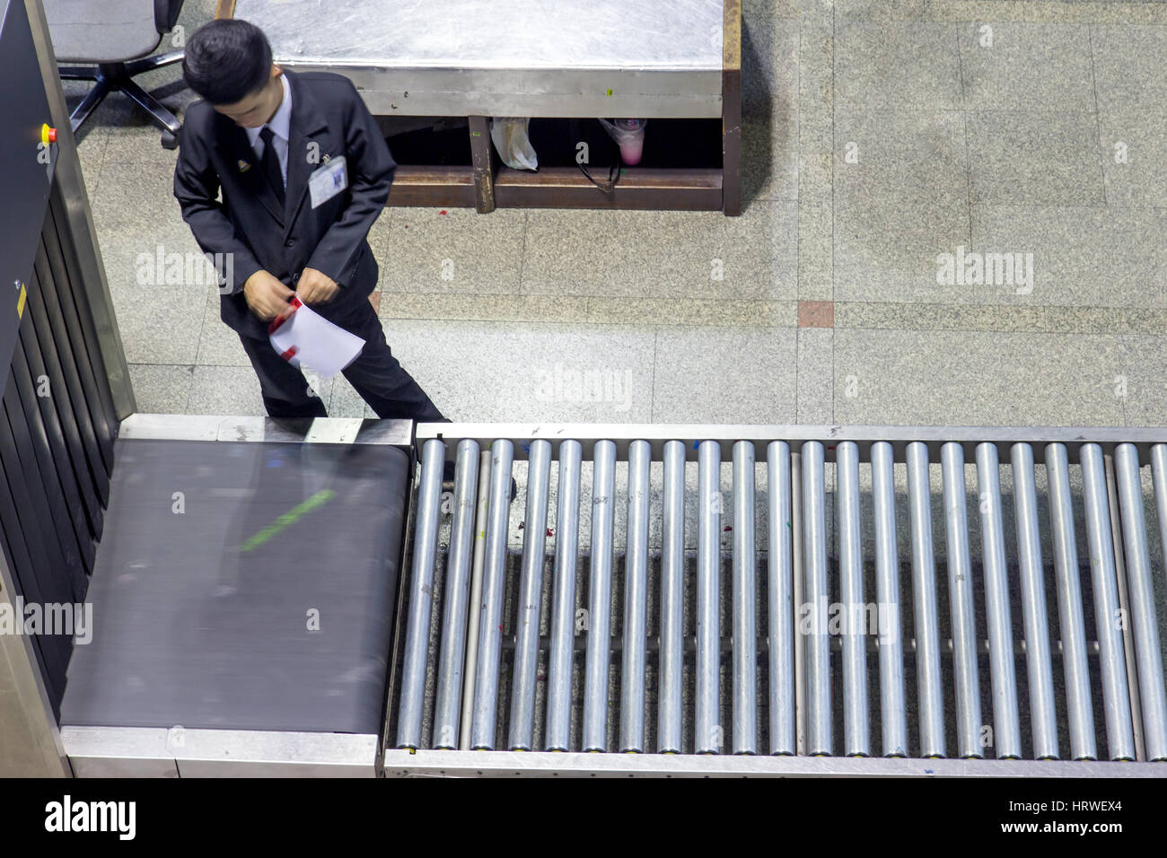 Controllare il bagaglio in aeroporto. Addetto alla sicurezza dell'aeroporto lavora a scanner per la verifica dei bagagli dei passeggeri prima della partenza. Foto Stock