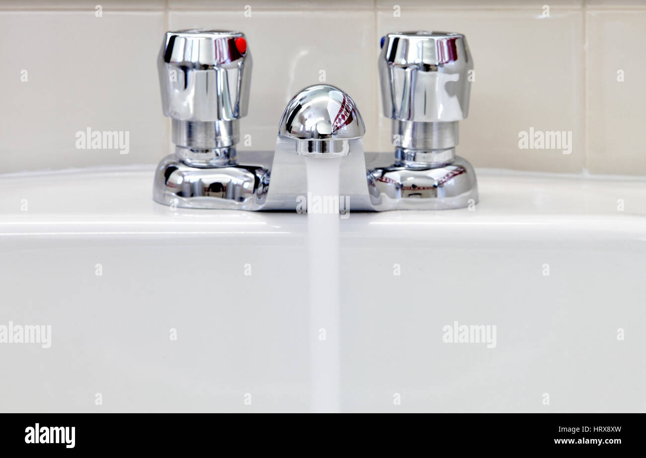 L'acqua che scorre al di fuori di un risparmio di acqua di rubinetto di conservazione installati in una toilette pubblica. Foto Stock