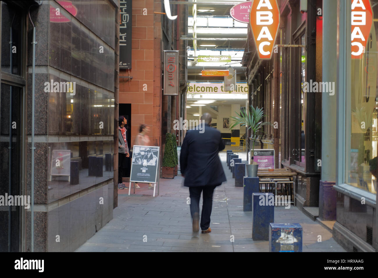 Colpo atmosferica di uomo a piedi sul telefono mobile nel quartiere alla moda di strada laterale Foto Stock