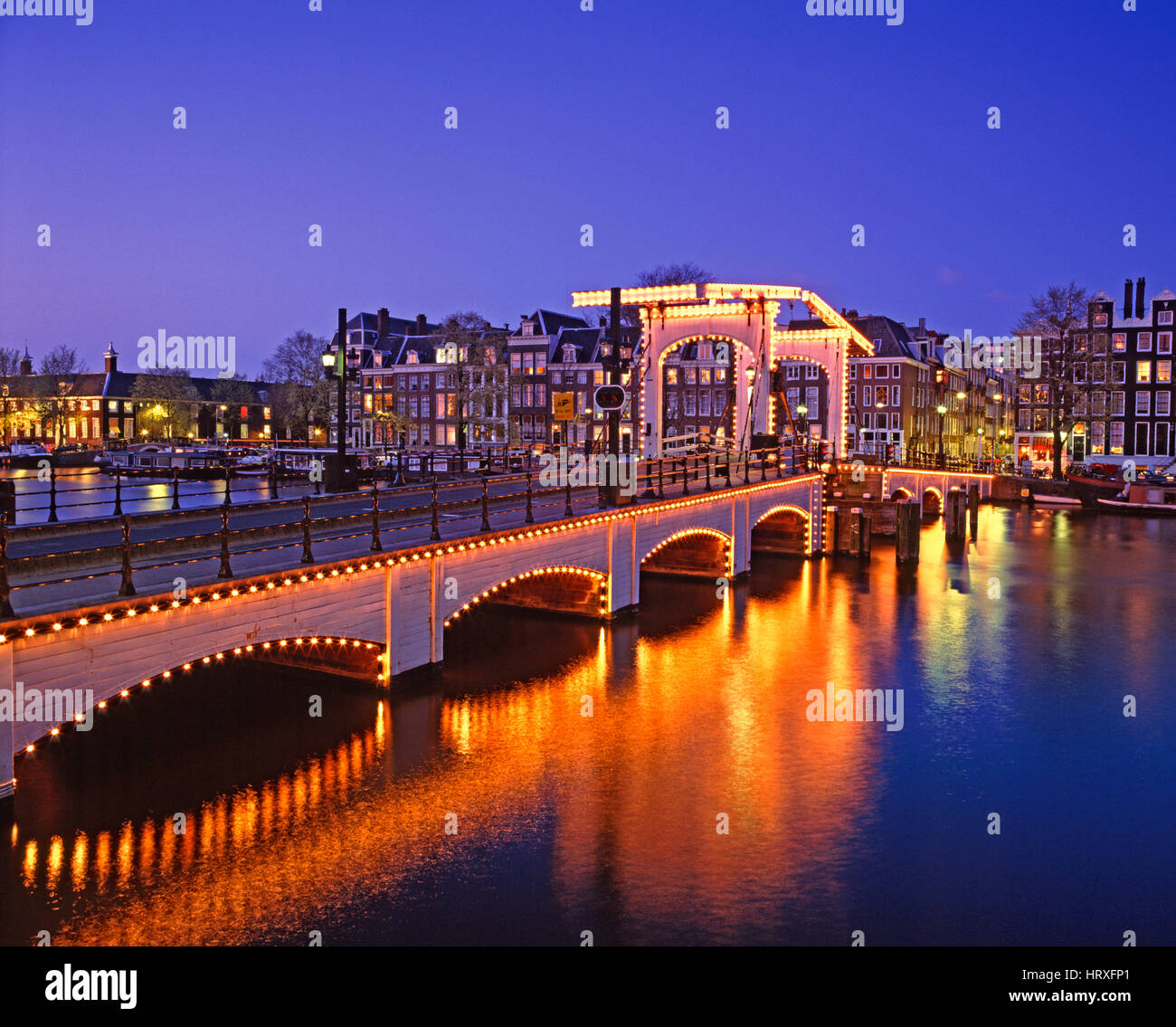 Skinny (ponte Magere Brug) riflettendo nel fiume Amstel di notte, Amsterdam, Olanda, Paesi Bassi Foto Stock