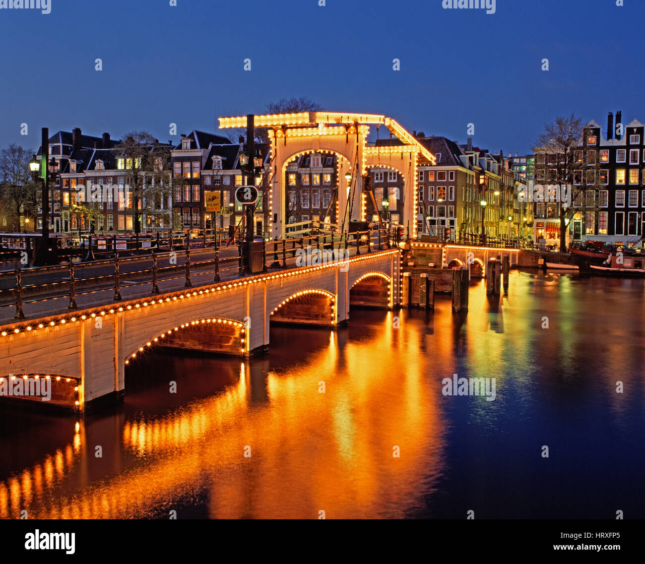 Skinny (ponte Magere Brug) riflettendo nel fiume Amstel di notte, Amsterdam, Olanda, Paesi Bassi Foto Stock