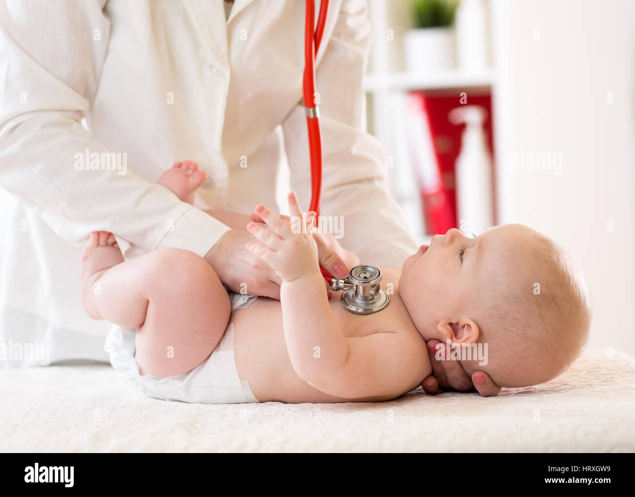 Pediatra esamina cinque mesi baby boy. Medico utilizzando uno stetoscopio per ascoltare il bambino petto controllare il battito cardiaco Foto Stock