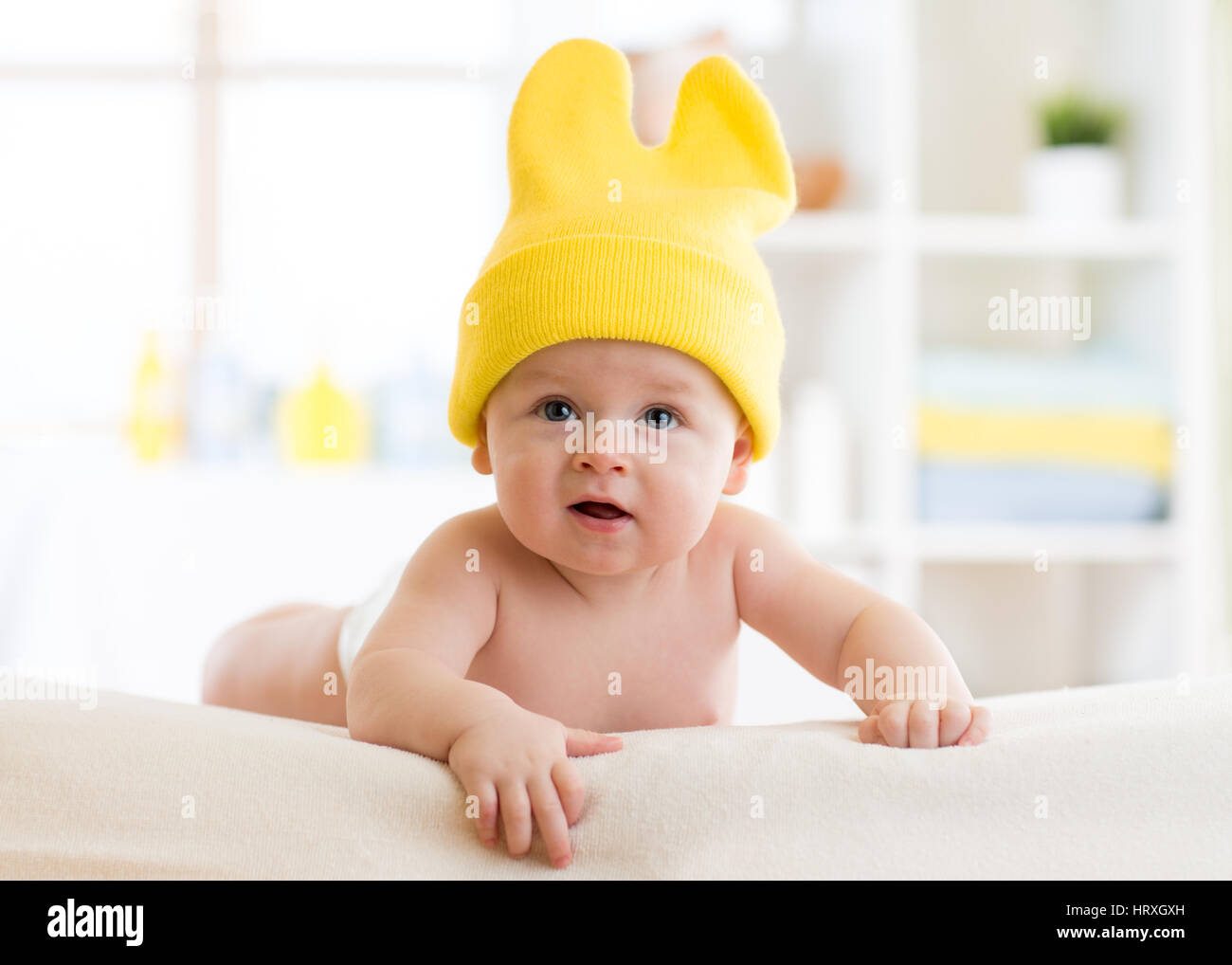 Baby divertente con il cappuccio sulla testa sdraiato sul letto di vivaio Foto Stock