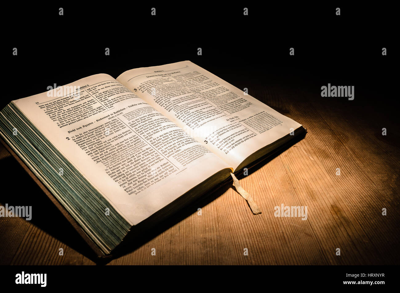Vecchia Bibbia su un tavolo di legno con sfondo scuro Foto Stock