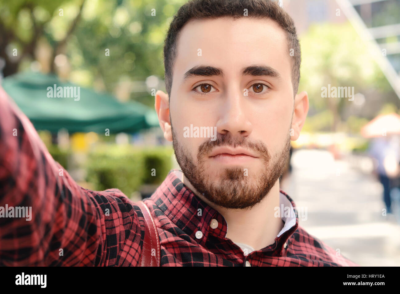 Giovane uomo latino tenendo un selfie. Scena urbana. All'esterno. Foto Stock