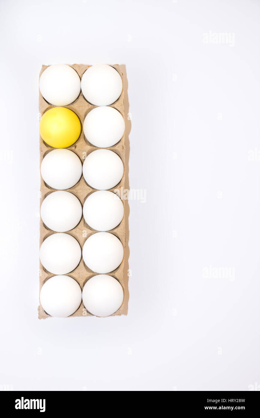 Un uovo di pasqua tinte di giallo e bianco undici di un uovo di gallina in una scatola di cartone da sopra con sfondo bianco e copia di spazio. Foto Stock