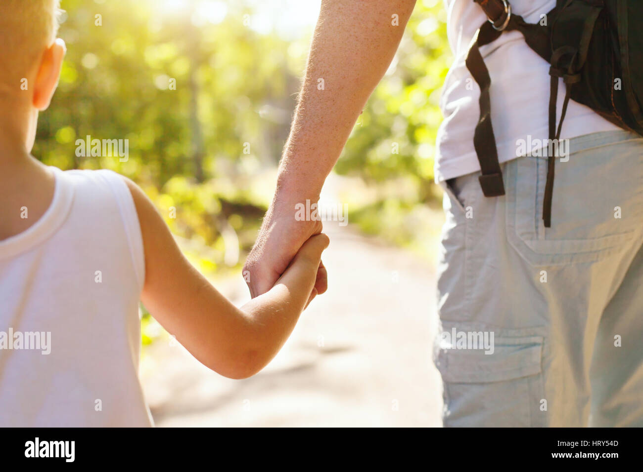 Bambino tenendo la mano del padre per adulti al di fuori in estate park Foto Stock