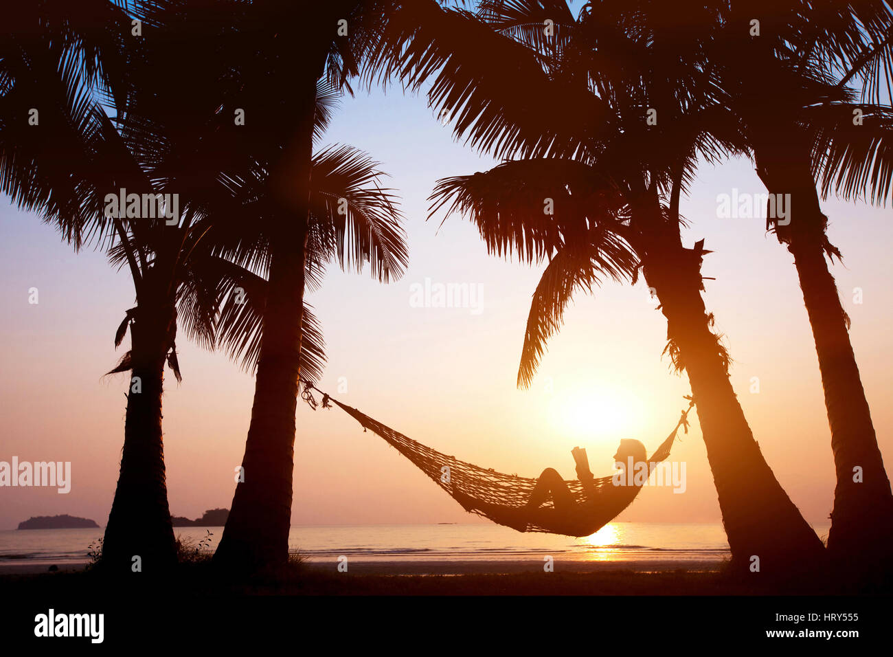 Donna relax in amaca sulla bellissima spiaggia del tramonto, concetto di vacanza Foto Stock