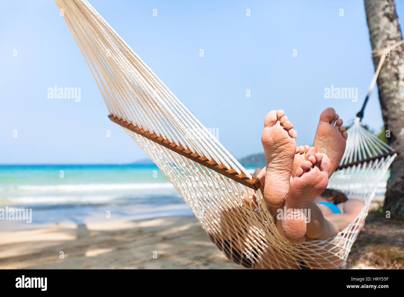 Coppia felice famiglia in amaca in Tropical Paradise beach, isola di vacanze, closeup dei piedi Foto Stock