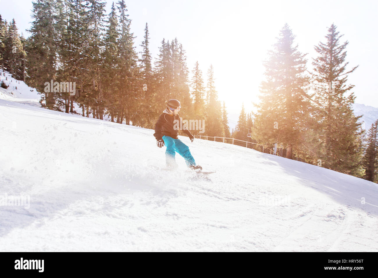 Snowboard in inverno alpi, uomo con velocità rapida su snowboard in pendenza di foresta con retroilluminazione Foto Stock