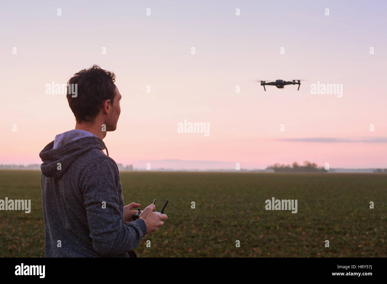 Uomo drone di pilotaggio al tramonto all'aperto Foto Stock
