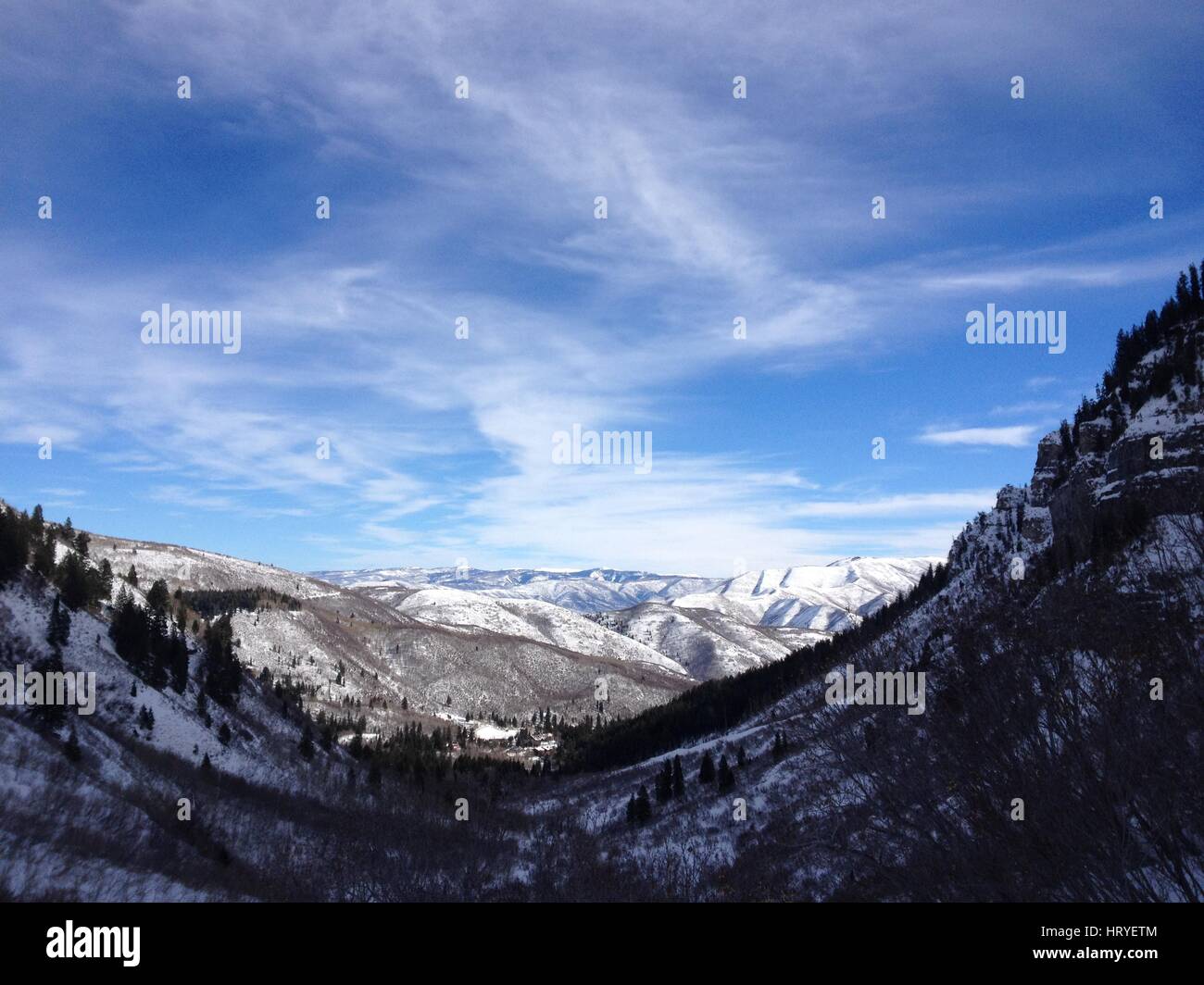 Wispy nuvole e blues cieli sopra coperta di neve Montagne Wasatch nello Utah County. Guardando verso il basso verso il Sundance e provo Canyon su un pomeriggio invernale Foto Stock