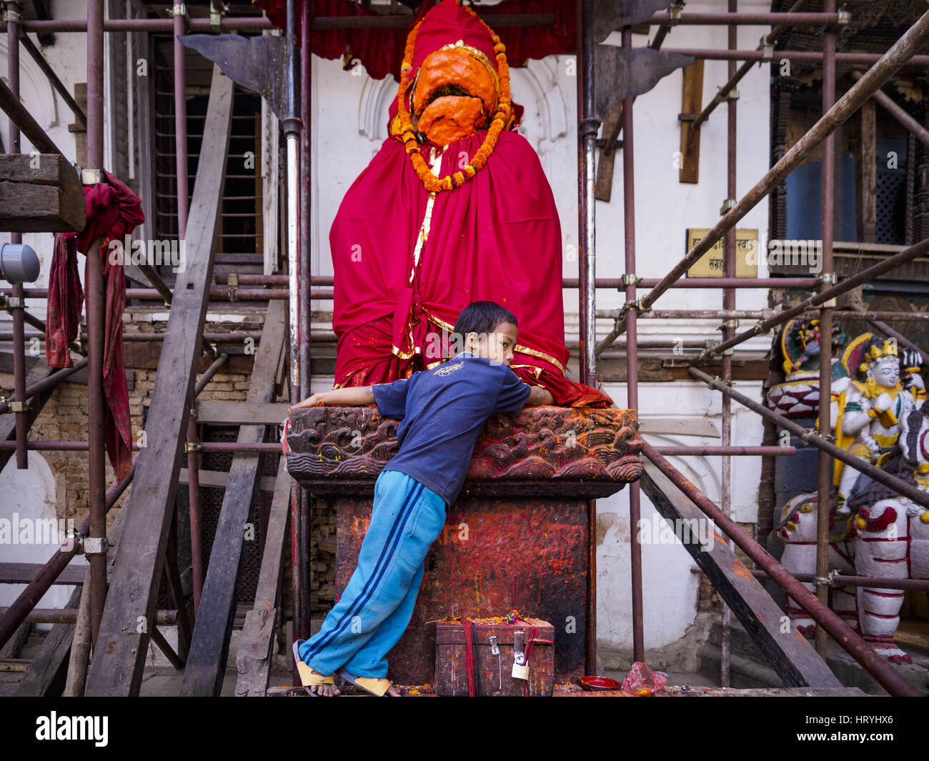Kathmandu, Sviluppo Centrale Regione, Nepal. Mar 5, 2017. Un bambino gioca su una statua di Hunaman, il dio indù è raffigurato come una scimmia, la statua è circondata da un ponteggio che è in attesa per la parete del Hanuman Dhoka Palazzo su Piazza Durbar di Kathmandu, un sito Patrimonio Mondiale dell'UNESCO gravemente danneggiata nel terremoto del 2015. Molto di Kathmandu è ora un sito in costruzione a causa della ricostruzione di due anni dopo il terremoto del 25 aprile 2015 che hanno devastato il Nepal. In alcuni villaggi della valle di Kathmandu i lavoratori stanno lavorando a mano per rimuovere il rublo e scavare edifici distrutti. Circa 9.000 pe Foto Stock