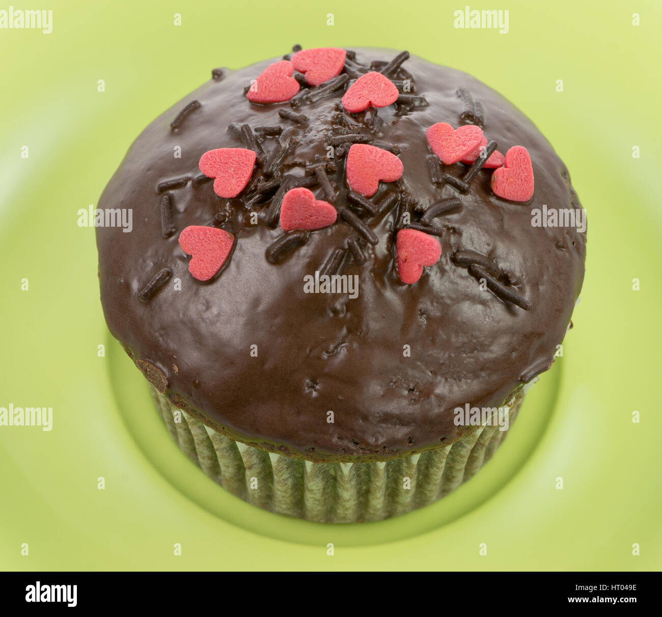 Muffin al cioccolato con zucchero rosso cuori su una piastra verde Foto Stock